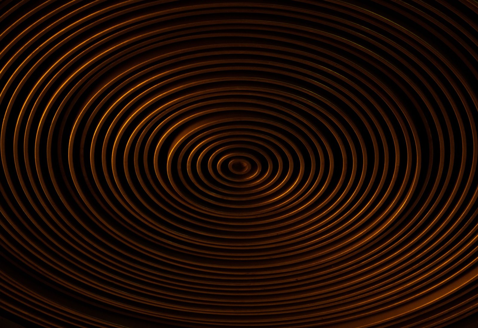 Concentric copper spirals on a dark background create a captivating abstract pattern.